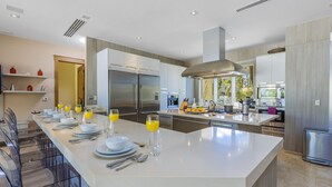 Una cocina moderna con una isla central, electrodomésticos de acero inoxidable y vistas al exterior.