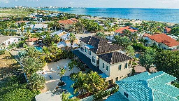 Un área residencial costera con casas, una piscina y vista al océano.