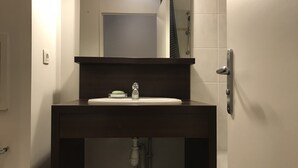 Une salle de bain avec un meuble-lavabo en bois foncé, un lavabo blanc et un miroir au-dessus.