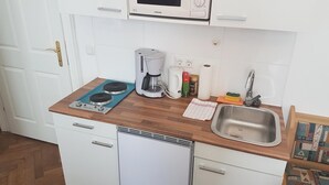 Una cucina compatta con forno a microonde, macchina del caffè, lavello e scolapiatti.