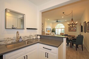 Een moderne keuken met een groot eiland, een ingebouwd spoelgedeelte en een spiegelende achterwand.
