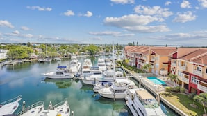 A marina with boats docked, a swimming pool, and residential buildings with balconies.