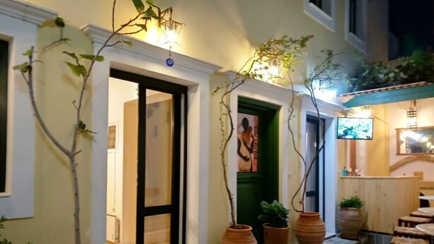Un espace extérieur bien éclairé, aménagé avec des sièges, des plantes en pot et une porte donnant accès à un espace intérieur.