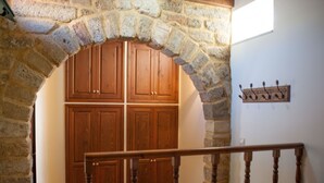 Une chambre à coucher avec une arche en pierre, une armoire en bois et un lit doté d’une tête de lit.