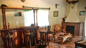 A rustic living room with a wooden bar, patterned floor, and a fireplace.