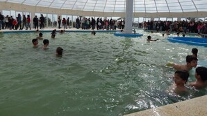 An indoor swimming pool with a large dome ceiling and a crowd of people around the pool area.