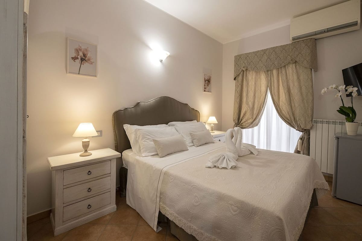 A neatly arranged bedroom with a bed, bedside tables, and a dresser.