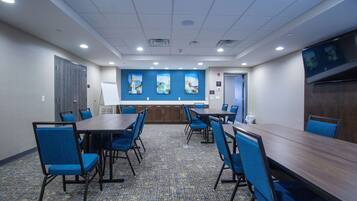 A conference room with a long table, blue chairs, and a carpeted floor.