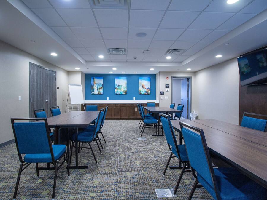 A conference room with a long table, blue chairs, and a carpeted floor.