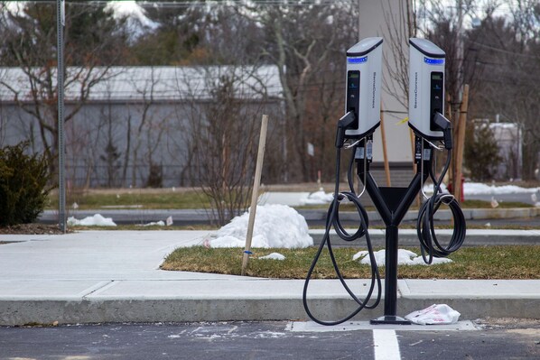Two electric vehicle charging stations on a sidewalk.
