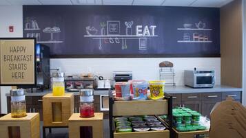 A breakfast area with a chalkboard wall, a sign that says 'HAPPY BREAKFAST STARTS HERE', and various breakfast items like cereal and yogurt.