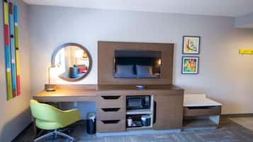 Habitación de hotel moderna con escritorio, silla, televisor y obras de arte.