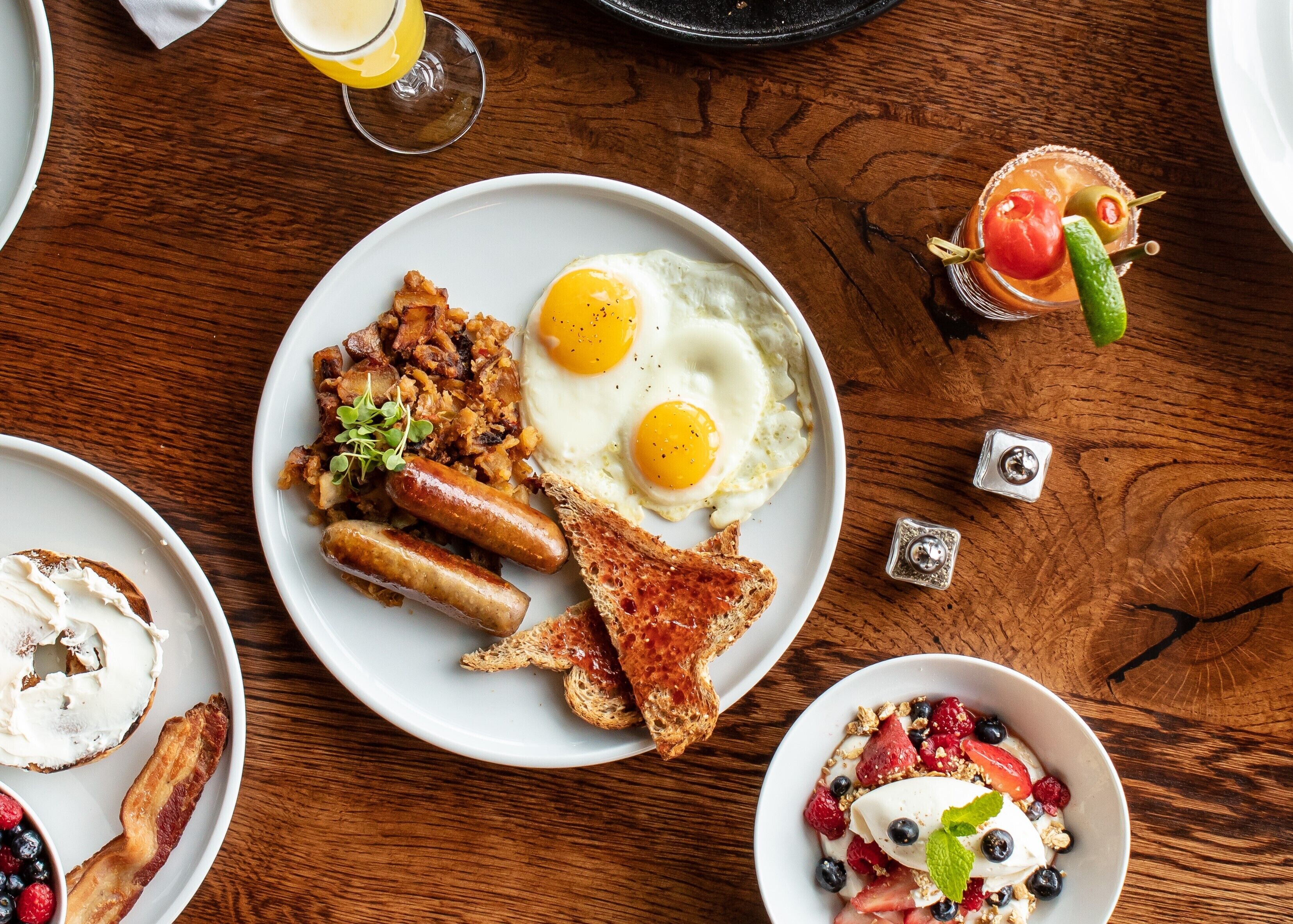 A breakfast plate with eggs, sausages, and toast on a wooden table.