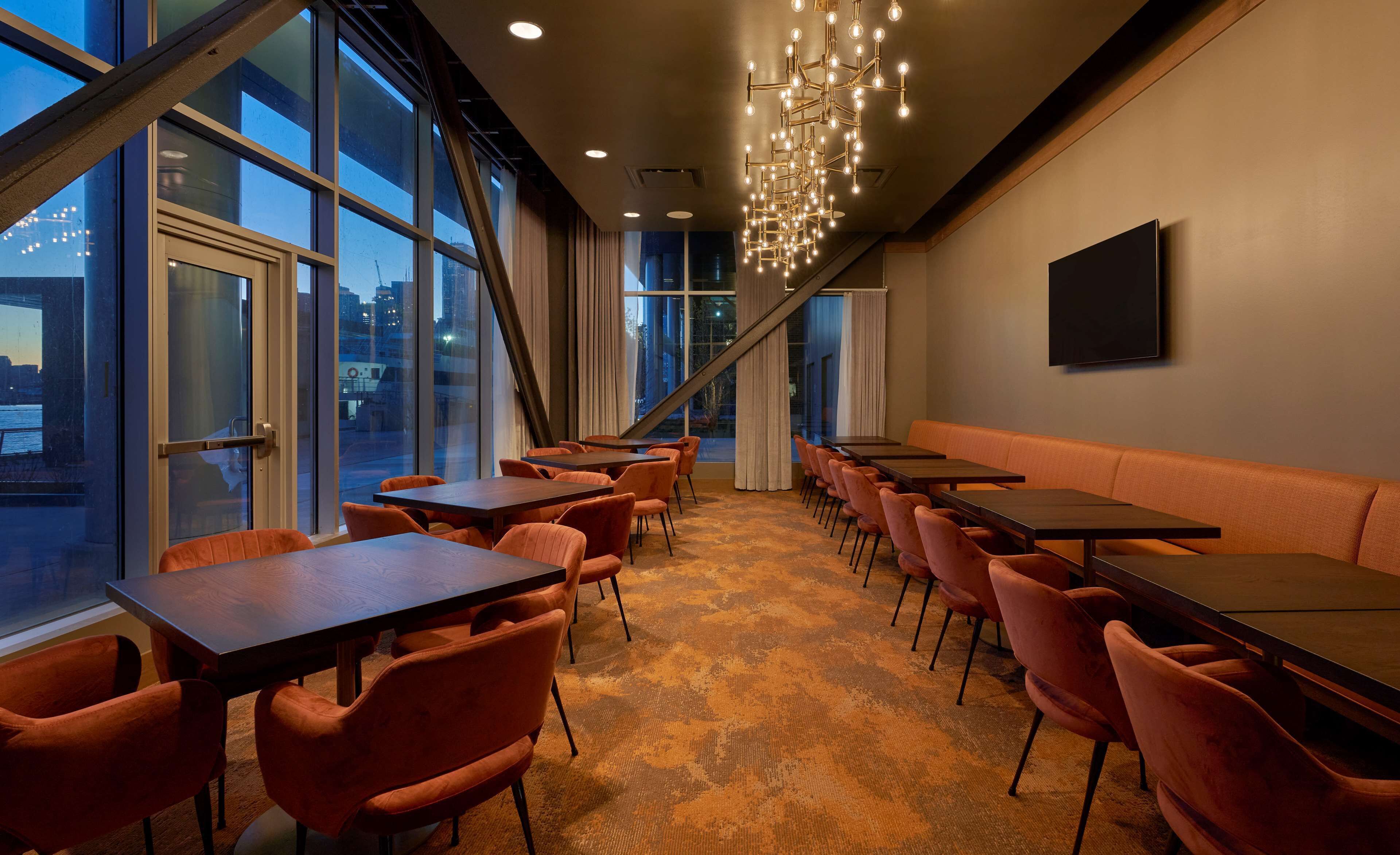 A modern dining area with large windows, a chandelier, and a seating arrangement.