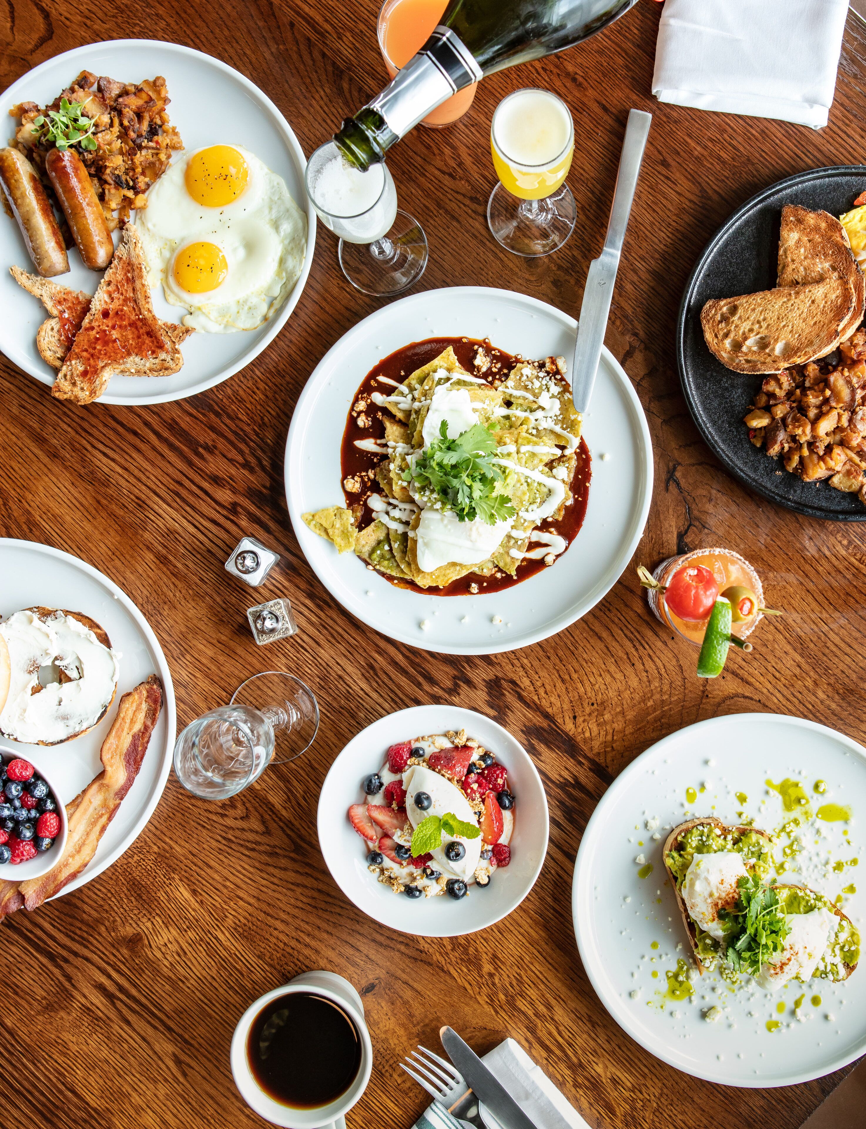 Una mesa de desayuno con diversos platos, incluyendo huevos, tostadas y un bol de fruta.