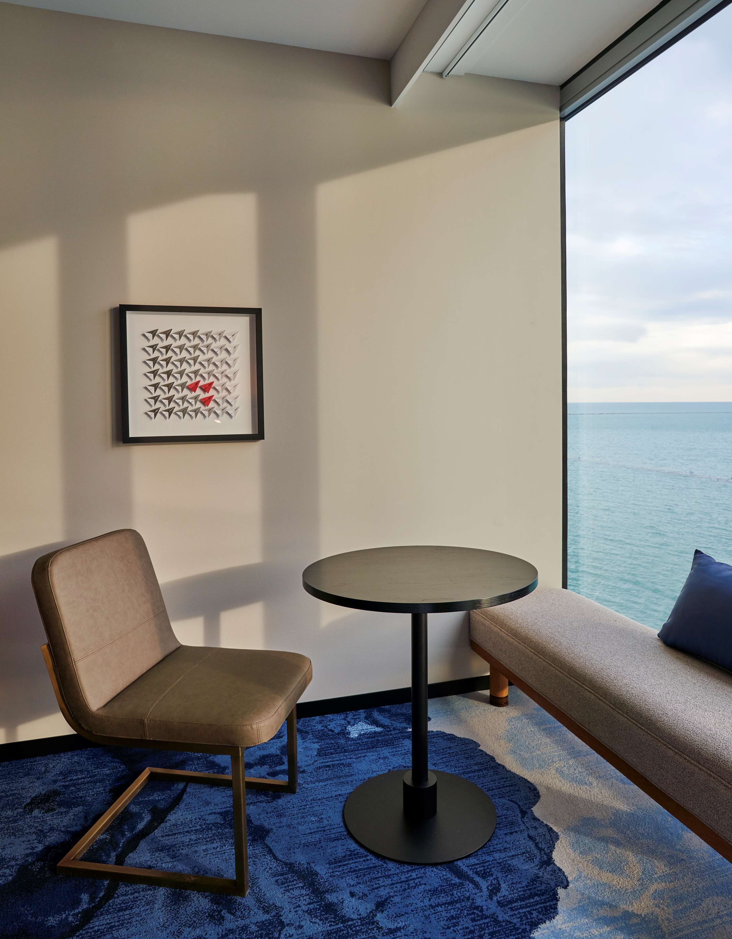 A modern room with a round table, a cushioned bench, and a framed abstract artwork on the wall.