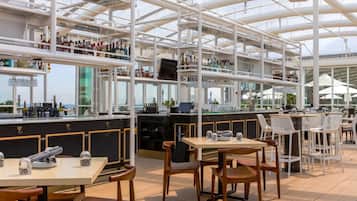 A spacious outdoor bar area with multiple seating options, including tables and chairs, and a variety of bottles and glasses on shelves.