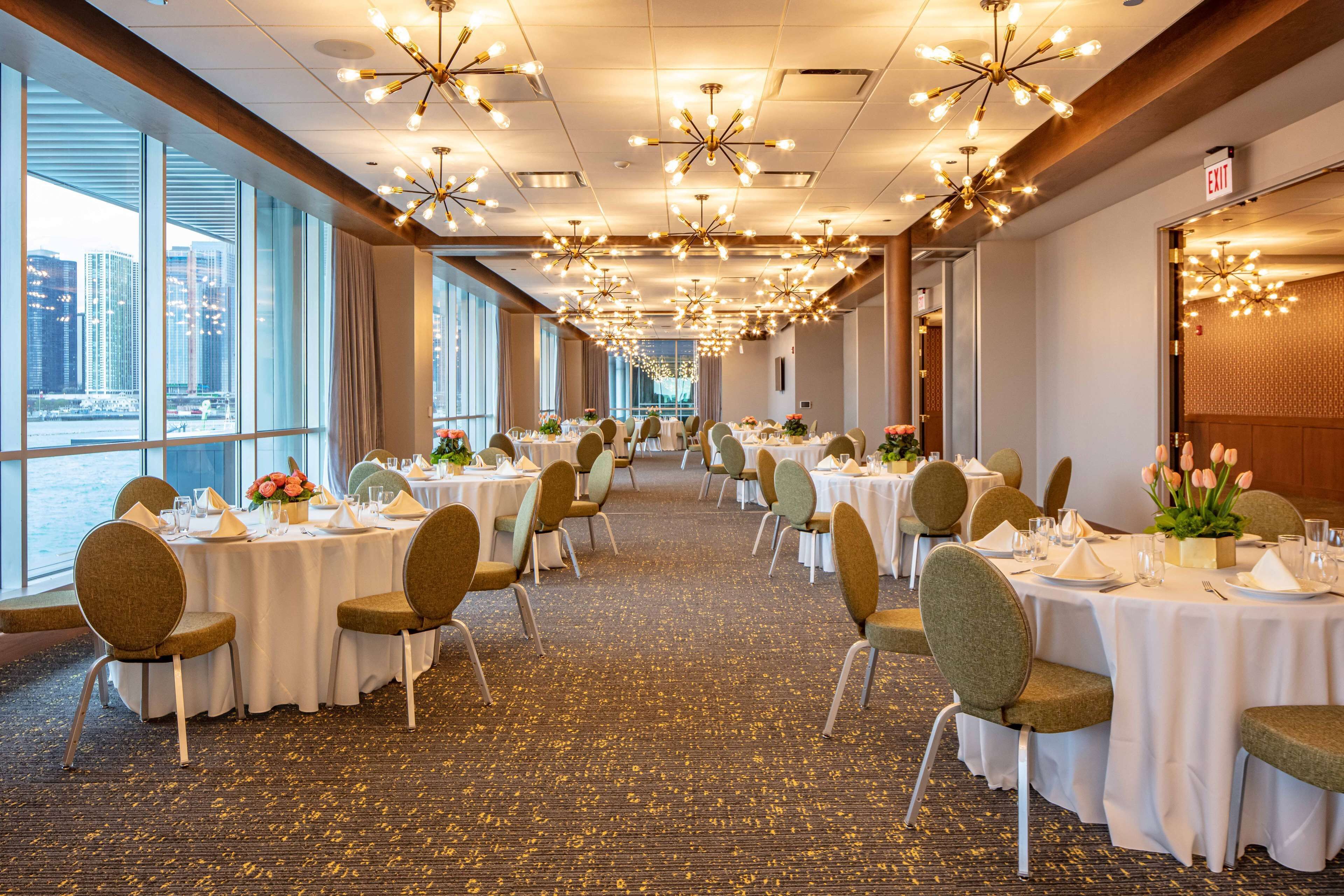 A banquet hall with round tables, chairs, and floral centerpieces.
