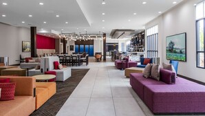 A spacious hotel lobby with seating areas, a dining area, and a bar. - Hilton Garden Inn Detroit Utica (Clinton Township)