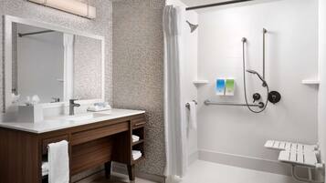 A modern bathroom with a vanity, a shower with a handheld showerhead, and a towel rack.