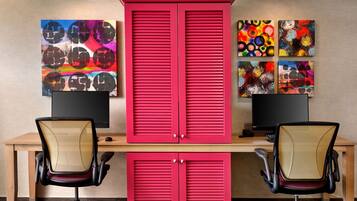 A workspace with two desks, each with a computer monitor, two office chairs, and a red cabinet with sliding doors.