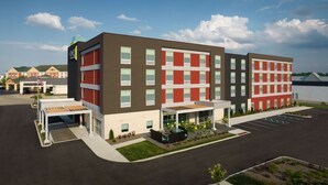 A multi-story hotel with a modern design, featuring a covered entrance area with seating and a landscaped garden. - Home2 Suites by Hilton Fishers Indianapolis Northeast, IN (Fishers)