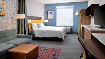 A hotel room with a bed, a sofa, a desk, and a television.