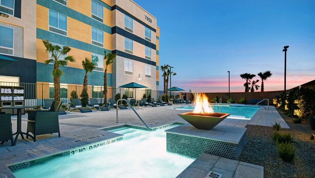 A hotel pool area with a fire feature, lounge chairs, and palm trees. - Hampton Inn Las Vegas Strip South, NV (Las Vegas)