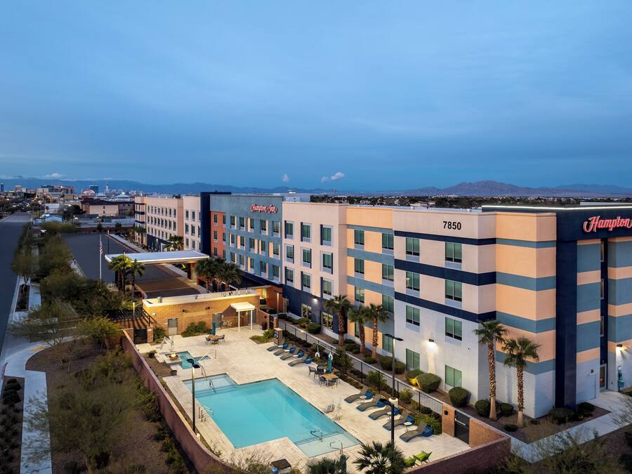 A hotel with a pool area, multiple floors, and a view of the cityscape.