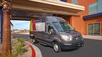 A Ford Transit van parked under a building with a 'Clearance 13' sign and a 'welcome' banner.