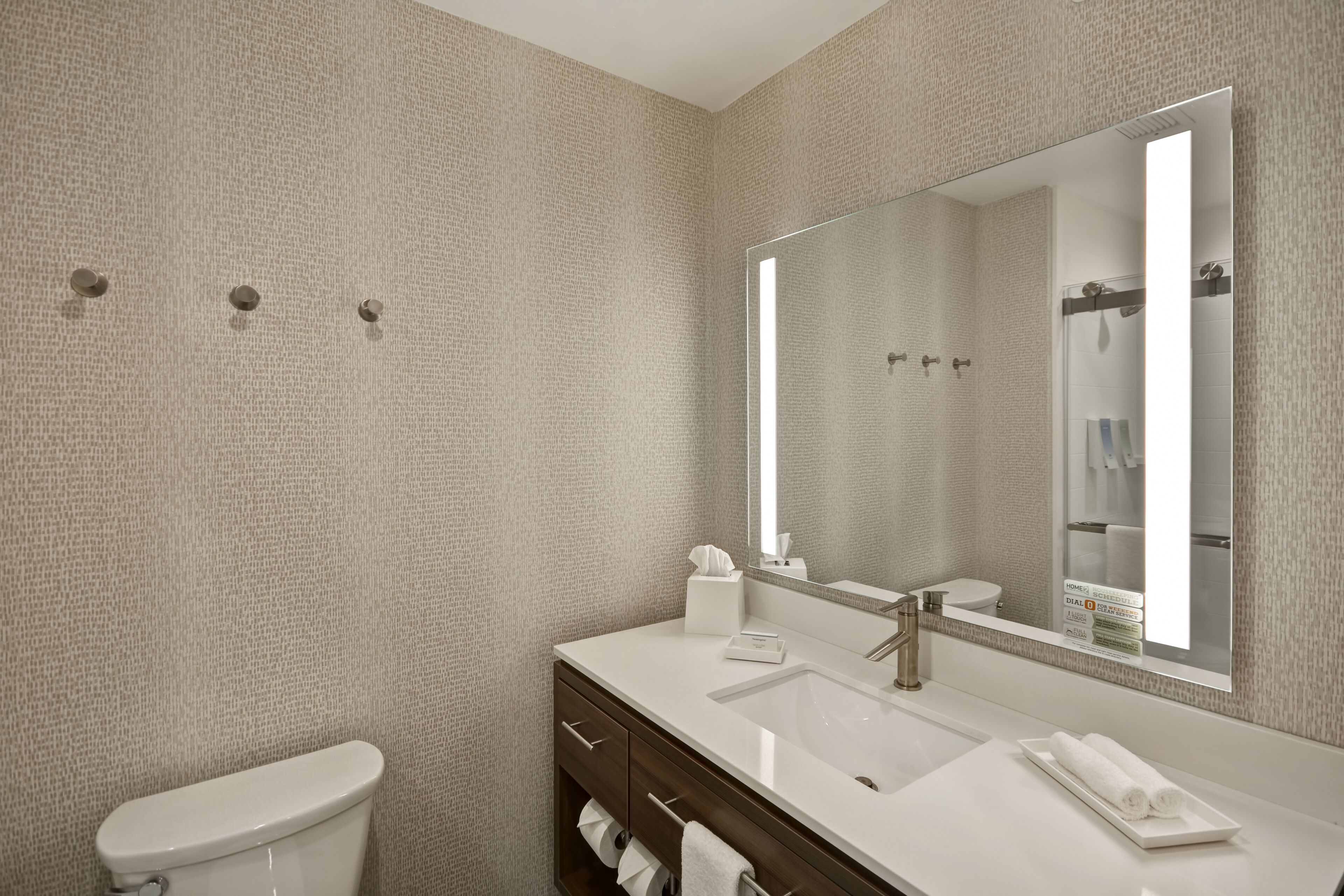 A modern bathroom with a large mirror, white sink, and a toilet.