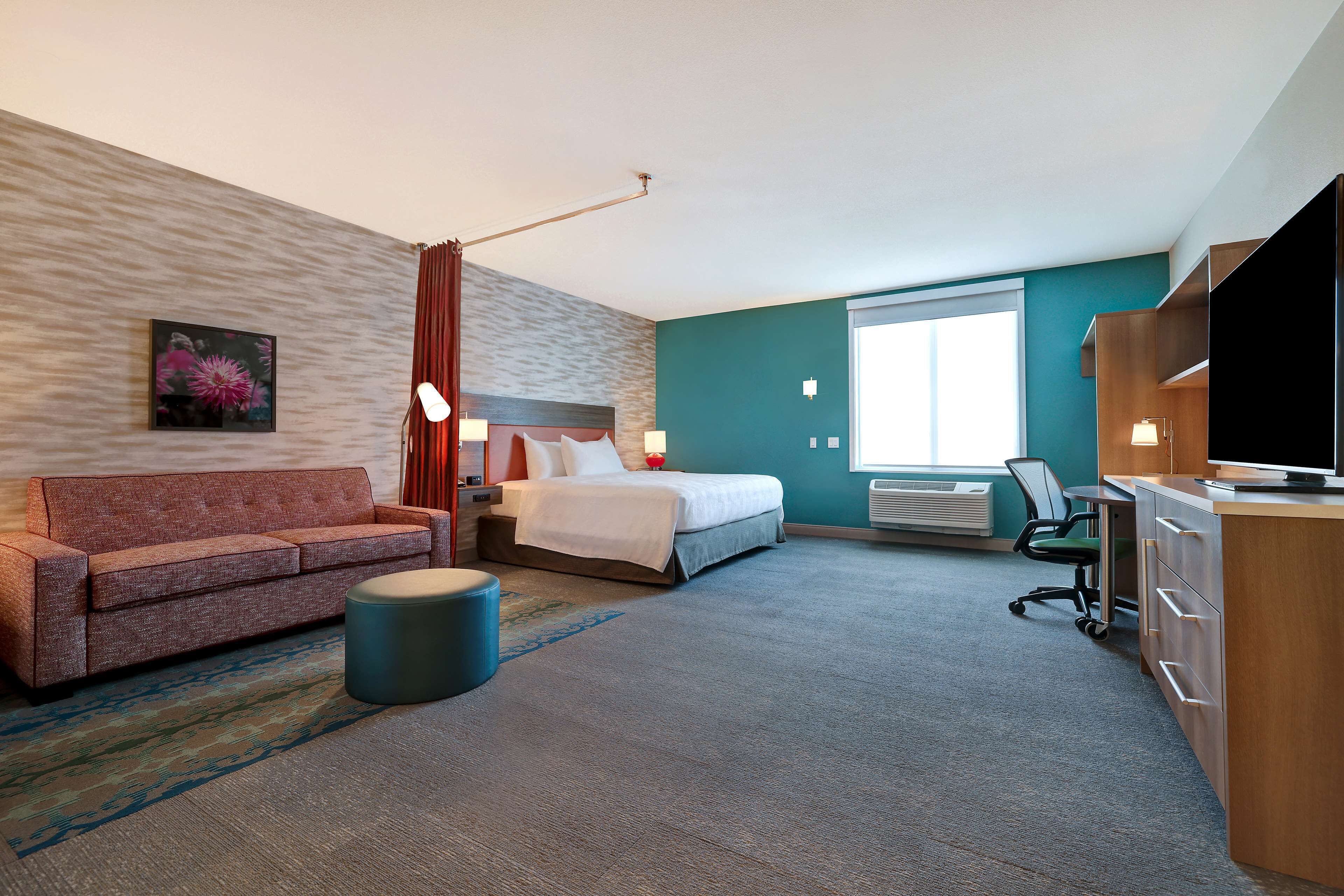 A hotel room with a bed, a sofa, a desk, and a television.