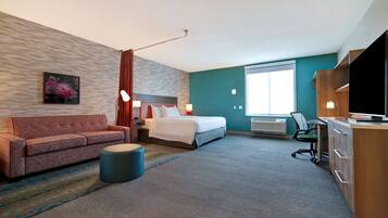 A hotel room with a bed, a sofa, a desk, and a television.