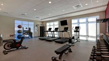 A gym with treadmills, an elliptical, a stationary bike, and free weights.