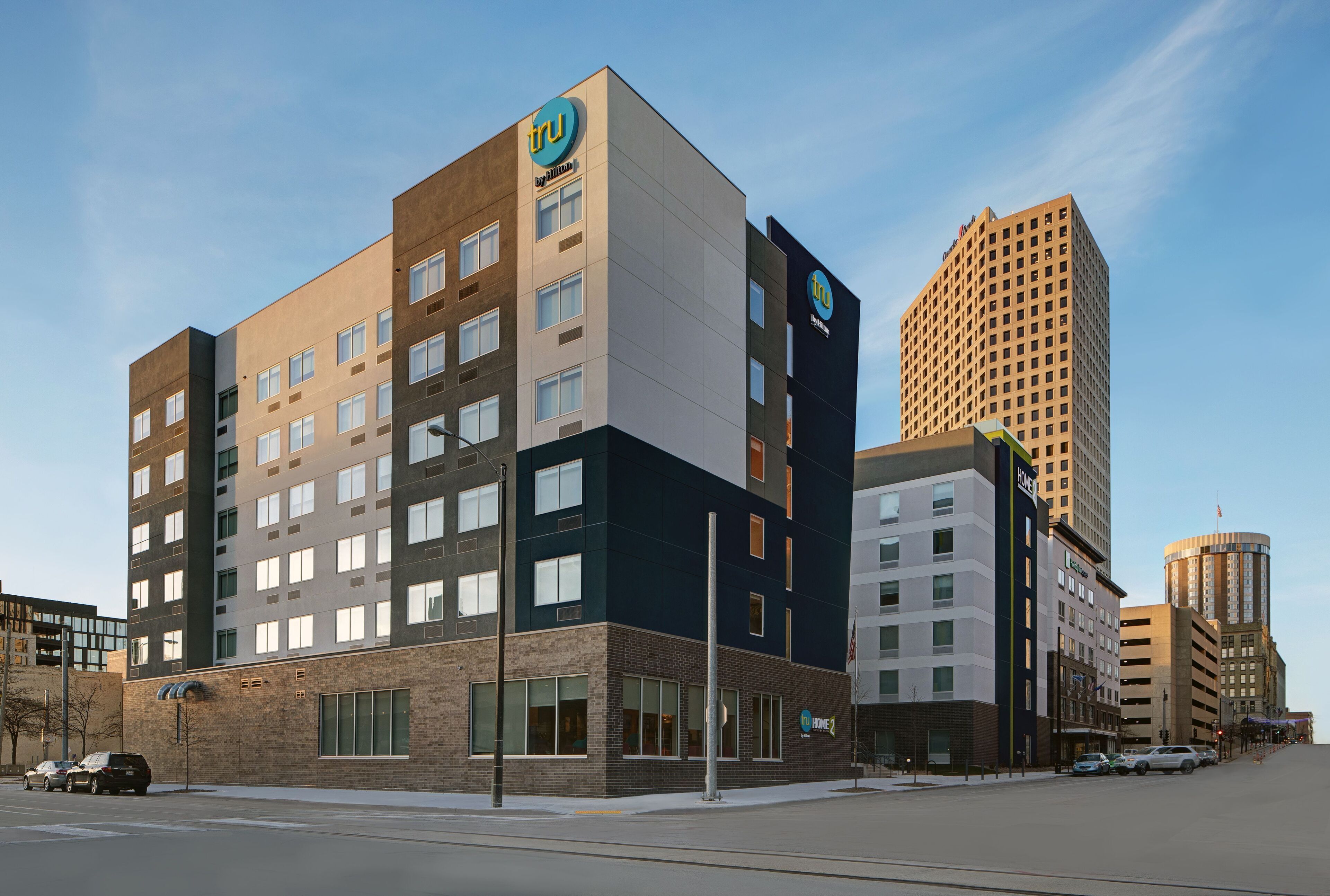 A multi-story hotel with a modern design, featuring a prominent 'tru' logo on the facade.