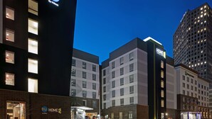 Un hotel con un llamativo letrero de 'tru by Hilton', varios pisos y un letrero que dice 'HOGAR', indicando un ambiente familiar.
