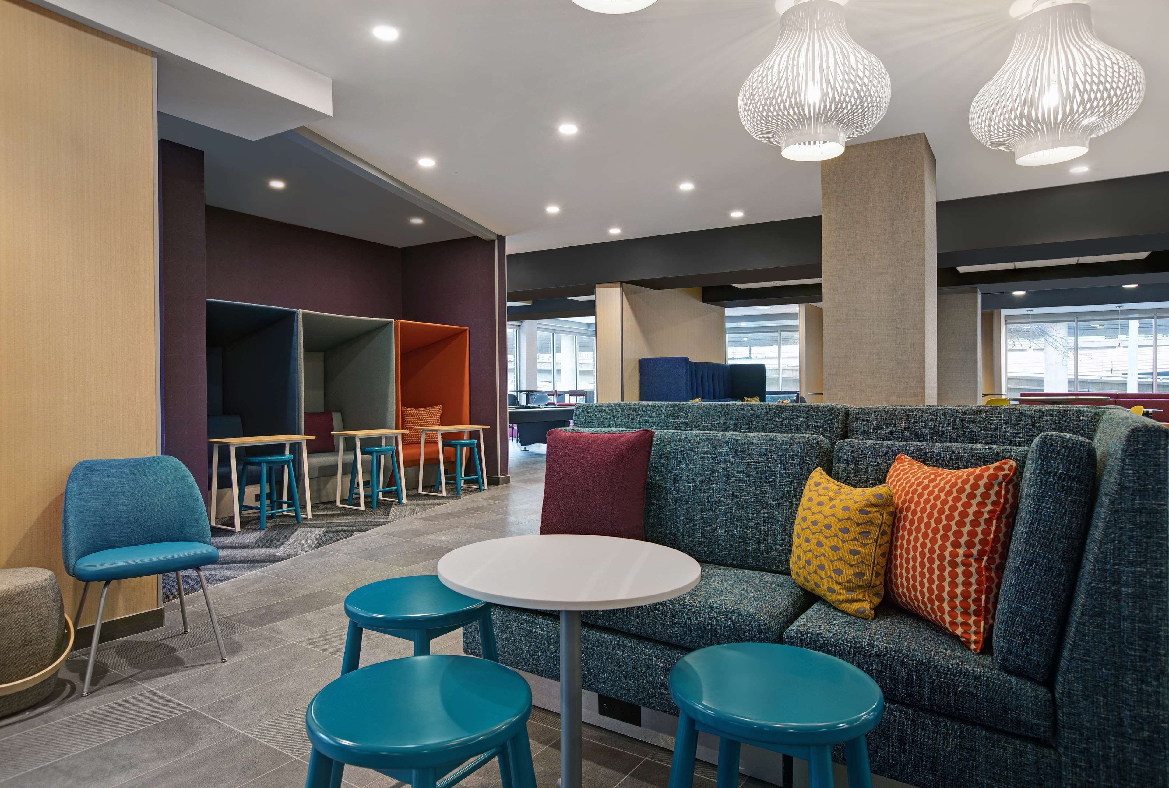 Un espace de détente moderne comprenant un canapé, des fauteuils et une table, avec différents types d’assises et une grande fenêtre laissant entrer la lumière naturelle.