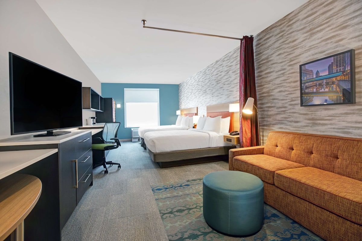 Een moderne hotelkamer met een bed, een bureau met een flatscreen-tv, een bank en een groot raam.