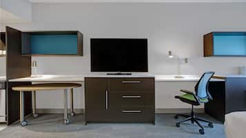 Una habitación de hotel moderna con un televisor de pantalla plana, un escritorio con silla y una mesita con ruedas.
