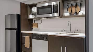 A modern kitchen with a stainless steel refrigerator, dishwasher, and microwave.