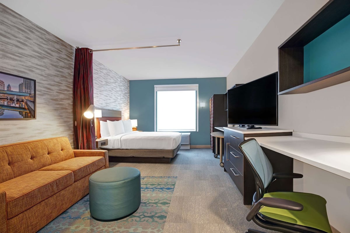 Een hotelkamer met een bed, een bureau, een televisie, een bank en een stoel.