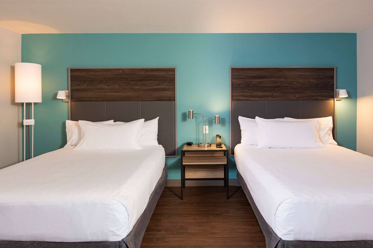 Ein Hotelzimmer mit zwei Betten, einem Nachttisch und einer Wandlampe.