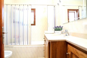 Een badkamer met een wastafel, spiegel en houten kastjes.