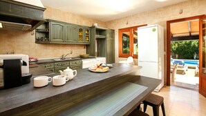 A modern kitchen with a large island, built-in cabinets, and a refrigerator. - BARRACA. Haven of peace 10 just min. walk to the centre (Puerto Pollensa)