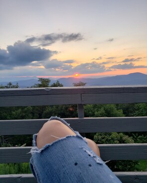 A sunset view from a wooden bench with a person's legs visible. - High Heaven 4 bed 3ba (Hendersonville)