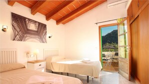A bedroom with two beds, a nightstand with a lamp, a wall-mounted light, and a view of the outdoors through an open door. - LLORENS (IVANA).  5 bedroom villa to enjoy with family and friends (Pollensa)