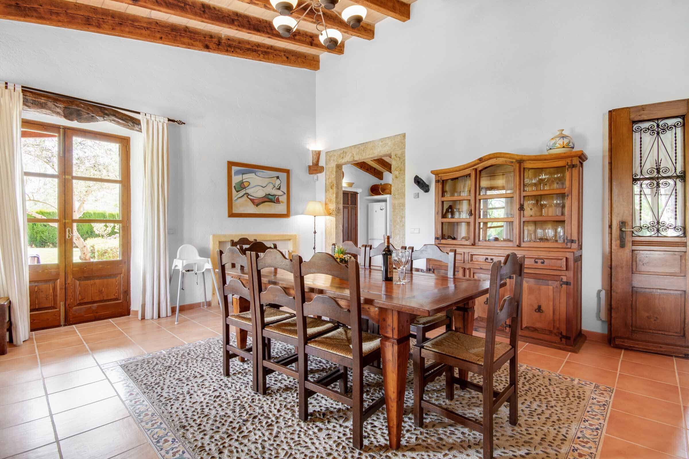 A dining area with a wooden table and chairs, a cabinet with glass doors, and a door with a decorative iron grille.