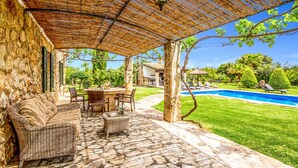 Une terrasse extérieure aménagée avec des meubles en osier, un mur en pierre et une vue sur une piscine.