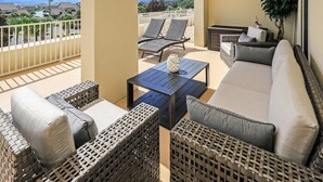 A balcony with wicker furniture, a table, and a sofa. - Large Private Balcony ~ Spacious Living Area (Miramar Beach)
