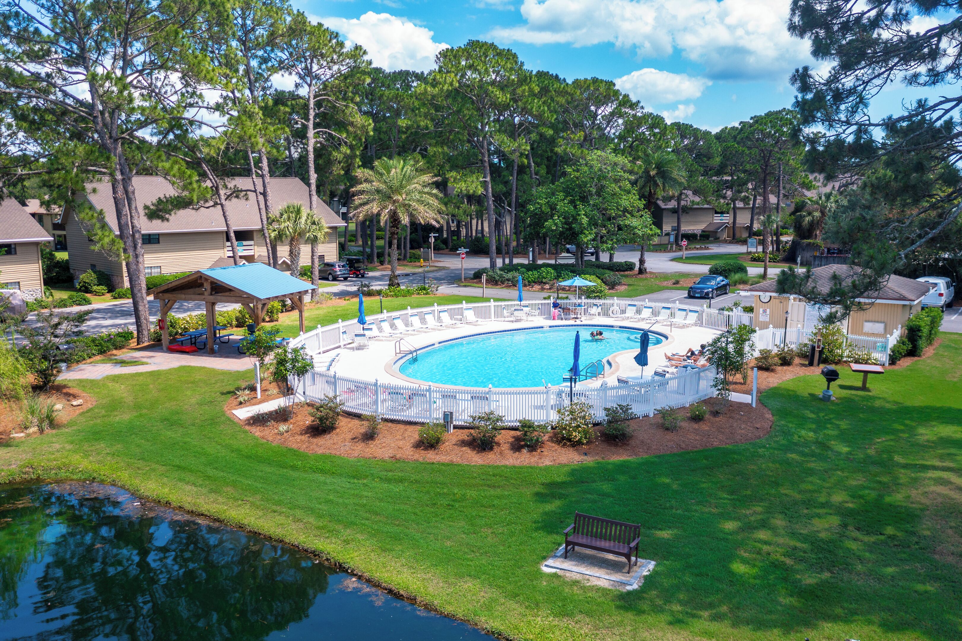 A residential area with a swimming pool, a fenced deck, and a small pond.